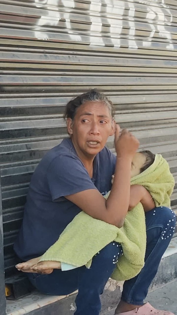 Madre camina con su hijo sin vida en brazos